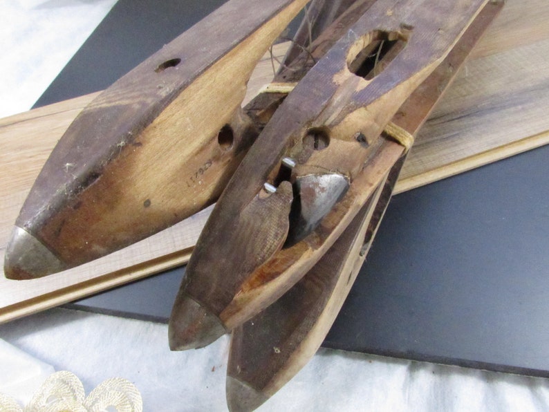 May include: Three wooden shoe lasts with metal tips. The lasts are stacked on top of each other. The top last has a metal piece attached to it. The lasts are made of wood and have a brown colour.