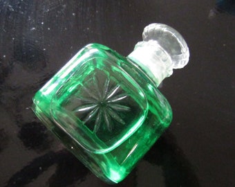 Puede incluir: Una botella de vidrio verde con un tapón de vidrio transparente. La botella tiene un diseño de estrella en la parte delantera.