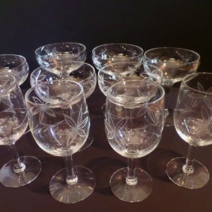 May include: Set of ten clear glass wine glasses with a delicate etched leaf design. The glasses have a round bowl and a long stem.