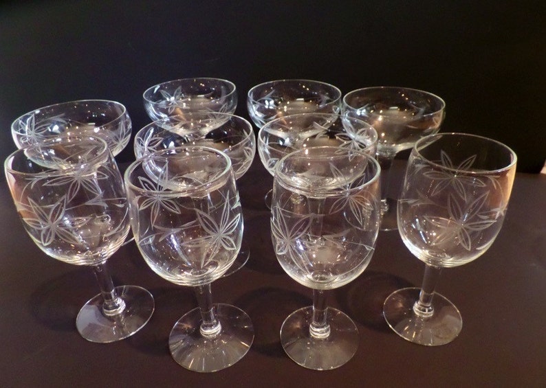 May include: Set of ten clear glass wine glasses with a delicate etched leaf design. The glasses have a round bowl and a long stem.