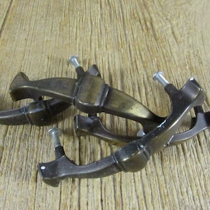 Puede incluir: Cuatro tiradores de puerta de armario de latón antiguo con un diseño único. Cada tirador tiene un tornillo para la instalación.