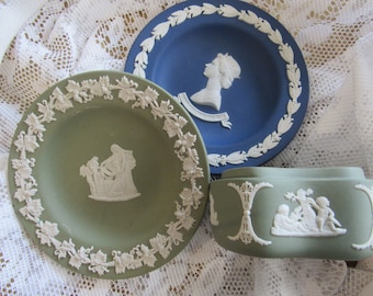 May include: Three Wedgwood style ceramic trinket dishes. One is blue with a white profile of Queen Elizabeth II and the text "EIIR 1952". The other two are green with white floral designs and white figures.