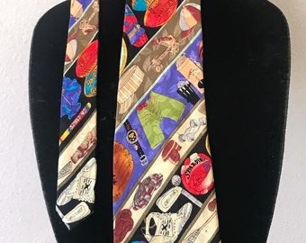 May include: A patterned necktie featuring a variety of sports equipment, including footballs, baseballs, and sneakers. The tie has a black background with diagonal stripes in various colors. The tie is displayed on a black mannequin.