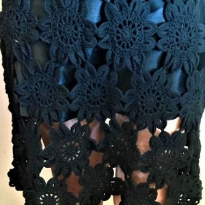 May include: Black crochet skirt with a floral design. The skirt is made of a delicate, openwork fabric and has a flowing silhouette.