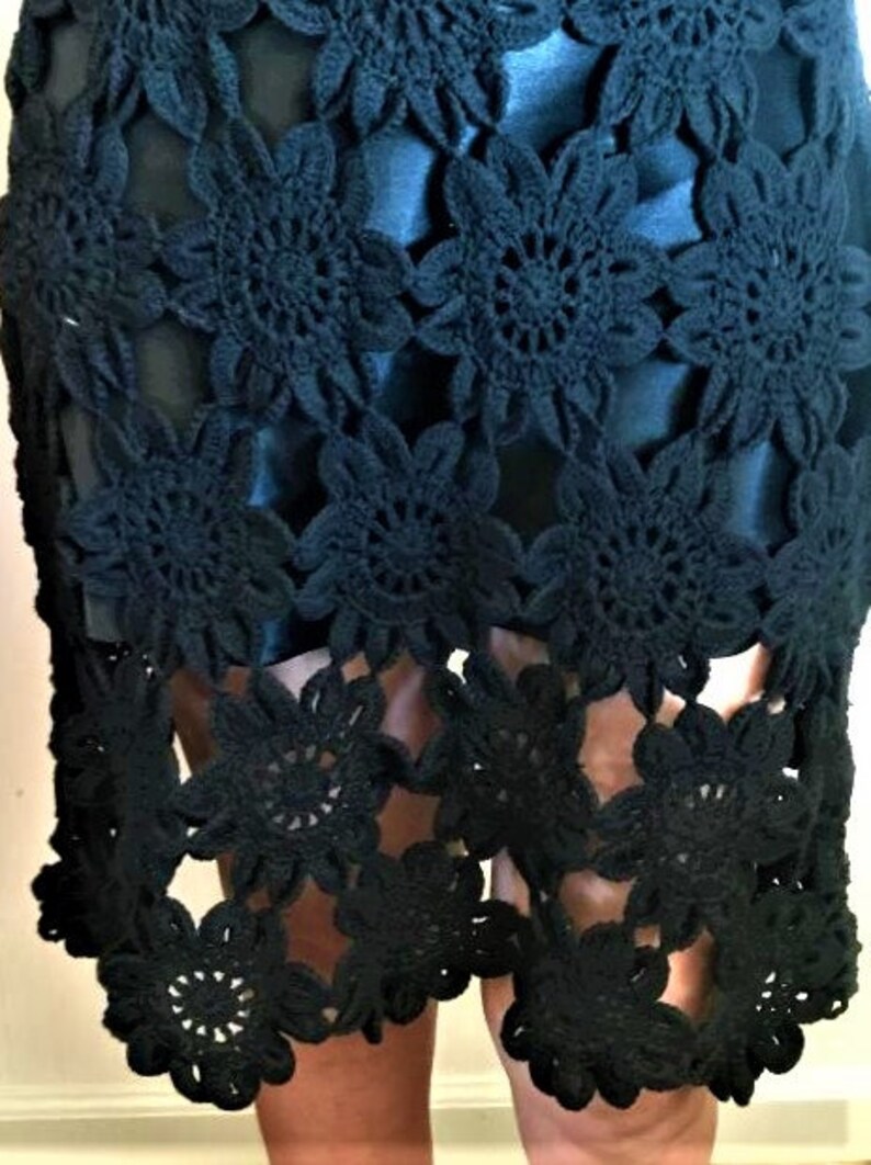 May include: Black crochet skirt with a floral design. The skirt is made of a delicate, openwork fabric and has a flowing silhouette.