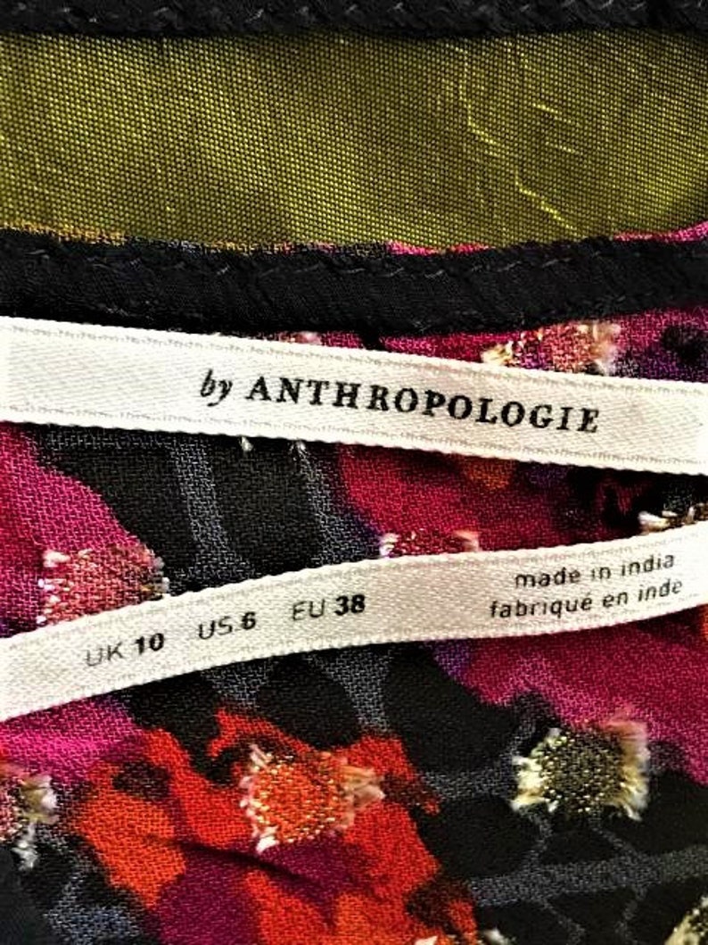 Może przedstawiać: Biała metka z czarnym tekstem "by Anthropologie" i biała metka z czarnym tekstem "UK 10 US 6 EU 38 made in india fabriqu&eacute; en inde"