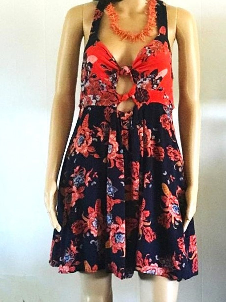 May include: A black and red floral print dress with a tie at the bust and a keyhole cutout. The dress has a fitted bodice and a flowy skirt.