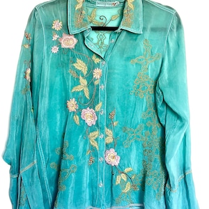 May include: A long-sleeved button-down shirt in a vibrant turquoise hue, featuring intricate gold thread embroidery and delicate pink floral accents. The garment includes a classic collar, a front button placket, and flared cuffs, showcasing detailed needlework across the front panels and collar.