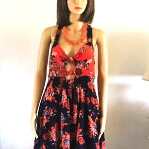 May include: A sleeveless floral dress with a red and black floral print. The dress has a halter neckline and a tie at the waist. The dress is made of a lightweight fabric and is perfect for summer.