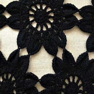 May include: Black crochet lace with a floral pattern. The lace is made of delicate, intricate stitches and has a classic, elegant look.