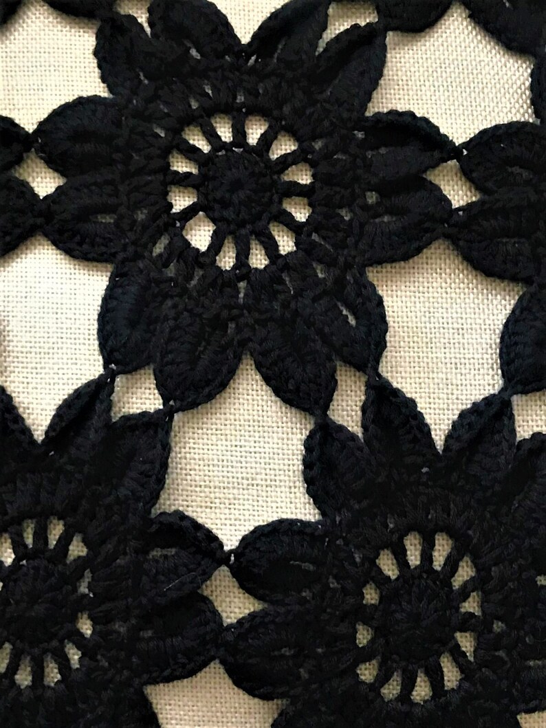 May include: Black crochet lace with a floral pattern. The lace is made of delicate, intricate stitches and has a classic, elegant look.
