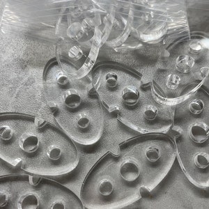 May include: A set of clear plastic stencils with various shapes and sizes. The stencils have multiple holes in them, creating a unique design.