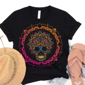 Puede incluir: Camiseta negra con un diseño de mandala colorido con una calavera en el centro. El mandala es un degradado de rosa, naranja, amarillo y verde.