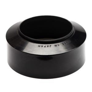 May include: A black, cylindrical lens hood with a smooth, glossy finish. The top rim features the embossed text MADE IN JAPAN. The object has a wide, circular opening at the top and a slightly narrower base, designed for camera lens attachment.