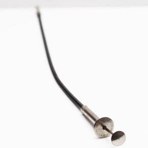 May include: A long, black, flexible retrieval tool with a silver metal tip and a circular handle. The handle has the text "MADE IN U.S.A." engraved on it.