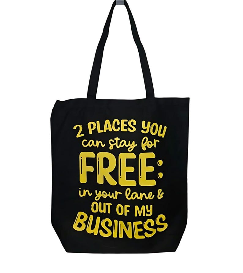 May include: Black canvas tote bag with yellow text that reads "2 PLACES YOU can stay for FREE: in your lane & OUT OF MY BUSINESS"