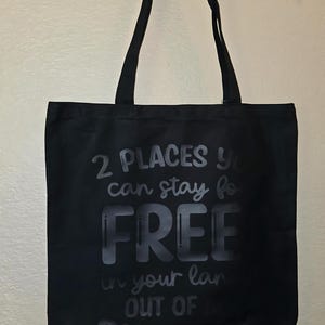 May include: Black tote bag with white text that reads "2 places you can stay for free in your land out of business".