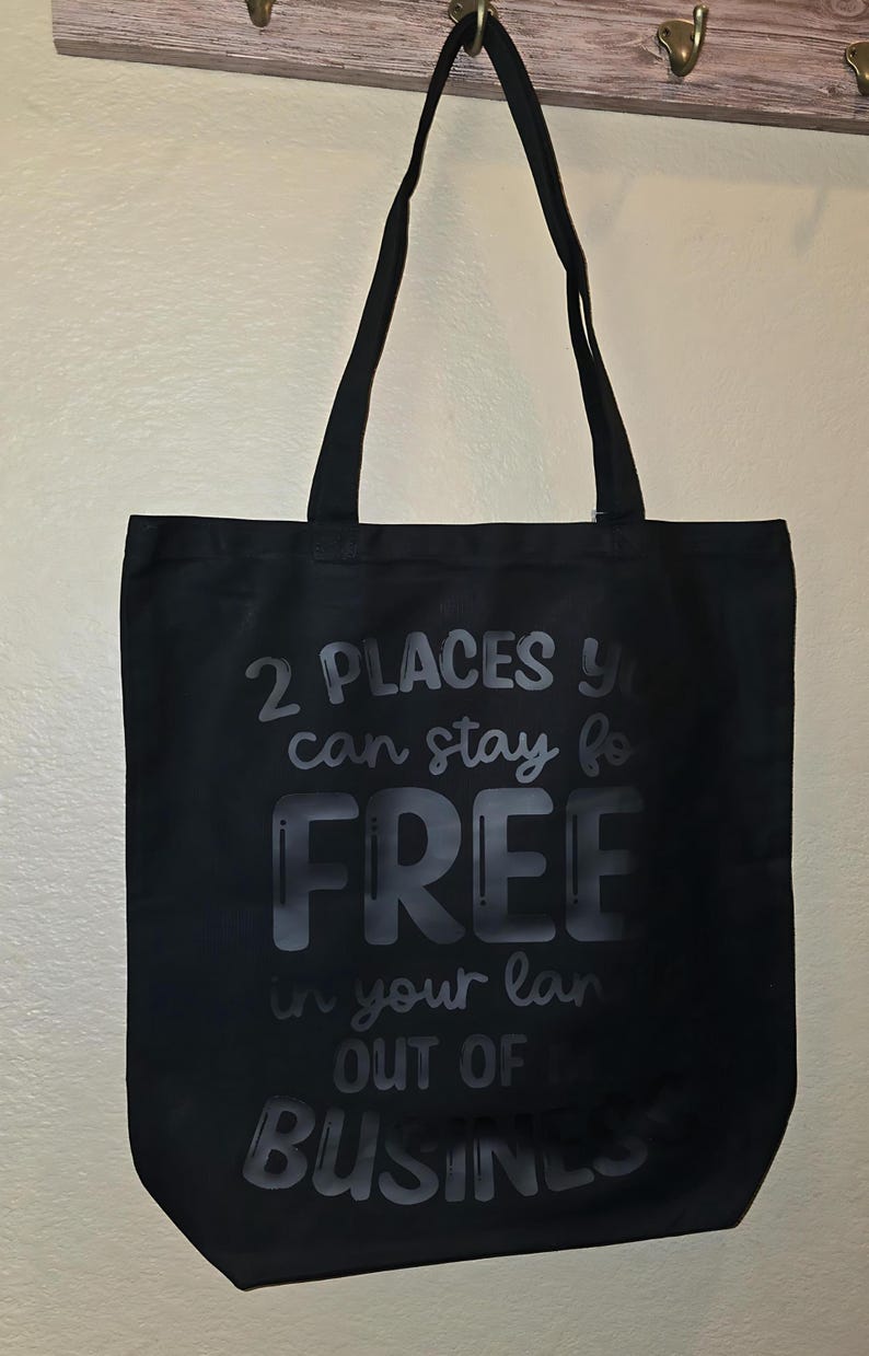 May include: Black tote bag with white text that reads "2 places you can stay for free in your land out of business".