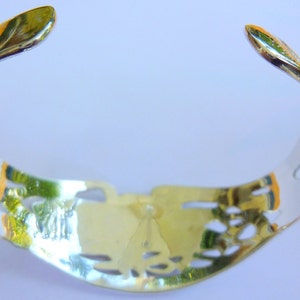 May include: A silver bracelet with a delicate, openwork design. The bracelet is made of polished metal and has a smooth, rounded finish.