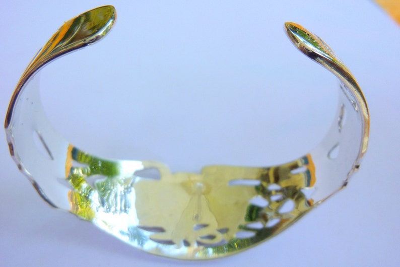 May include: A silver bracelet with a delicate, openwork design. The bracelet is made of polished metal and has a smooth, rounded finish.