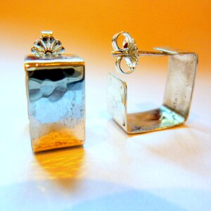 May include: A pair of silver square earrings with a hammered finish. The earrings have a post and butterfly fastening.