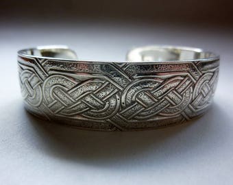 May include: Silver Celtic knot cuff bracelet with a textured finish.