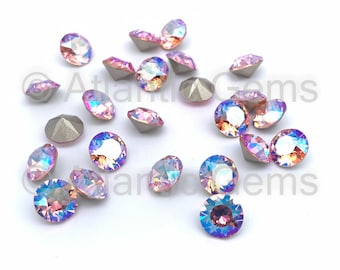 May include: A scattering of iridescent pink and blue rhinestones, with a silver backing, on a white surface.