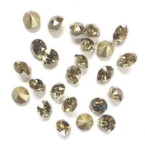 May include: A collection of round, faceted, metallic gold and bronze-toned crystals. Each piece features a pointed back and a multi-faceted top surface that reflects light, creating a sparkling appearance across the various individual stones.