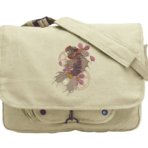 Könnte beinhalten: Eine beige Canvas-Messenger-Tasche mit einem gestickten Design eines Steampunk-Drachen mit rosa Blumen und Zahnrädern.