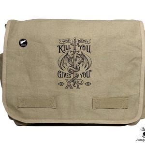 May include: A beige canvas messenger bag with a black and white graphic of a dragon and sword. The graphic says "What Doesn't Kill You Gives You XP".