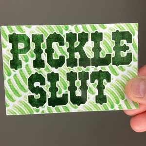May include: A green and white card with the text "PICKLE SLUT" in black letters.