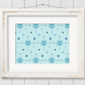 May include: A framed print featuring a repeating pattern of compass roses and stars in shades of blue on a light blue background. The compass roses are oriented with the cardinal directions labeled. The frame is white and ornate.