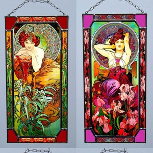 Könnte beinhalten: Vier Bleiglasfenster mit Illustrationen von Frauen im Jugendstil mit floralen Motiven. Jedes Fenster hat ein anderes Farbschema und Design, mit einer Kette, die von oben hängt.