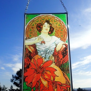 Könnte beinhalten: Ein Buntglasfenster, das eine Frau in einem weißen Kleid mit roten Blumen zeigt. Die Frau hält eine rote Blume in der Hand. Der Hintergrund ist ein grünes und goldenes Design.