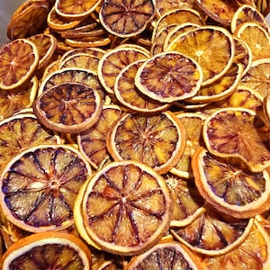 May include: A bowl filled with dried orange slices. The slices are a deep orange colour with a brown hue. They are arranged in a random pattern.