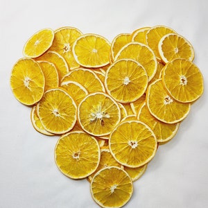 Puede incluir: Una forma de corazón hecha de rodajas de naranja secas. Las rodajas están dispuestas en forma de corazón sobre un fondo blanco.