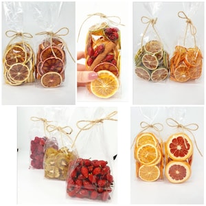 Pode incluir: Conjunto de frutas secas e fatias de citrinos embaladas em sacos de plástico transparentes. Os sacos são amarrados com barbante e apresentam uma variedade de cores, incluindo vermelho, laranja, amarelo e verde.