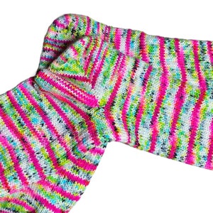 Puede incluir: Un par de calcetines a rayas de colores en tonos de rosa, verde, blanco y negro. Los calcetines est&aacute;n hechos de un tejido suave y de punto.