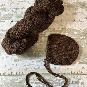 May include: A brown knitted baby hat and a skein of brown yarn.