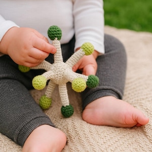 Sonajero de diente de león a crochet, juguete suave y moderno en verde y blanquecino, hecho a mano por TomToy.
