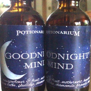 May include: Two dark brown glass bottles with blue labels. The labels have a crescent moon and stars with the text "POTIONARIUM GOODNIGHT MIND". The text on the labels lists ingredients including passionflower, fruit, motherwort, and chamomile.