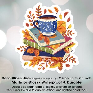 May include: A sticker featuring a blue coffee mug with a white pattern, sitting on top of a stack of books with autumn leaves. The sticker is available in matte or gloss finishes and is waterproof and durable. The sticker is 2 inches up to 7.5 inches in size.