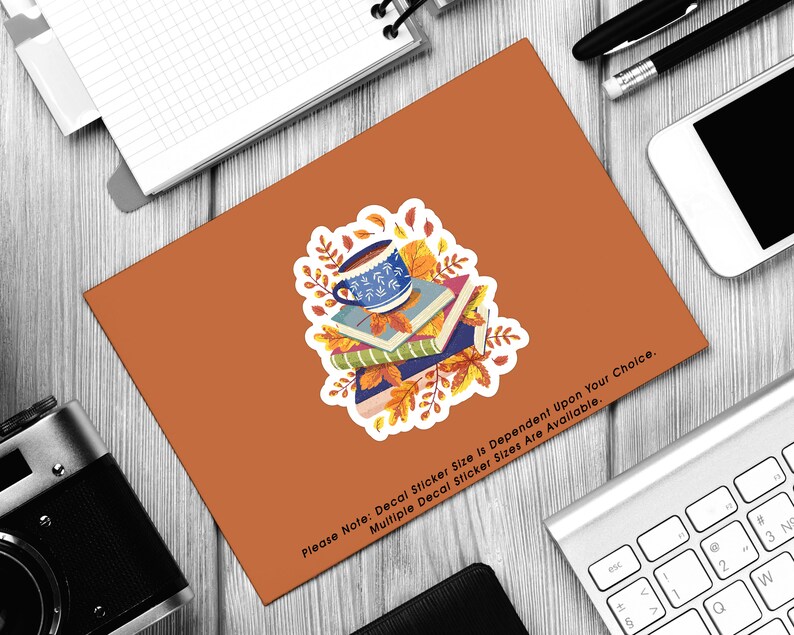 May include: A sticker featuring a blue and white coffee mug with a stack of books and autumn leaves. The text "Please Note: Decal Sticker Size is Dependent Upon Your Choice. Multiple Decal Sticker Sizes Are Available." is at the bottom of the sticker.