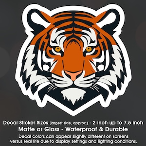 May include: A tiger face decal sticker in orange, black, and white. The sticker is available in sizes from 2 inches to 7.5 inches. It is waterproof and durable, and can be used on a variety of surfaces.