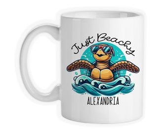 May include: White ceramic mug with a cartoon sea turtle wearing sunglasses and the text "Just Beachy ALEXANDRIA" in black.