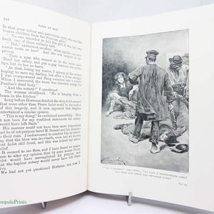 Może przedstawiać: Otwarta książka z czarno-białą ilustracją przedstawiającą scenę z kilkoma postaciami, w tym mężczyzną w długim płaszczu i kapeluszu oraz kilkoma postaciami na podłodze. Tekst na stronie jest w języku angielskim.