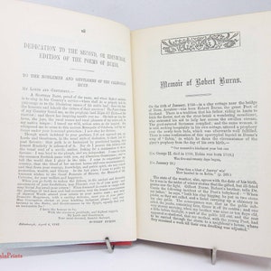 Pode incluir: Um livro antigo aberto com p&aacute;ginas cor de creme e texto impresso em preto. A p&aacute;gina esquerda intitula-se Dedication to the Second, or Edinburgh Edition of the Poems of Burns. A p&aacute;gina direita intitula-se Memoir of Robert Burns.