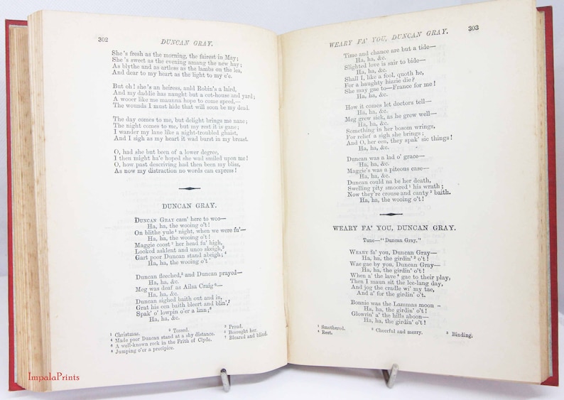 Pode incluir: Um livro aberto com p&aacute;ginas cor de creme apresentando o texto impresso em preto do poema Duncan Gray e Weary Fa' You, Duncan Gray. As p&aacute;ginas est&atilde;o numeradas 302 e 303, com capas vermelhas vis&iacute;veis nas bordas e notas de rodap&eacute;.