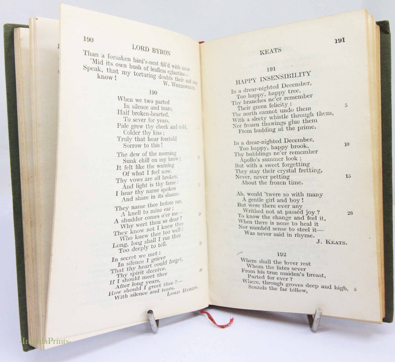 May include: An open book showing poetry by Lord Byron and Keats. The book has a green cover and a red ribbon bookmark. The pages are aged with visible text.