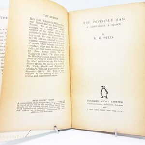 Op de afbeelding: Open boek getiteld "The Invisible Man" van H.G. Wells, uitgegeven door Penguin Books Limited. De biografie van de auteur staat op de linkerpagina. Het boek wordt opengehouden met een metalen standaard.